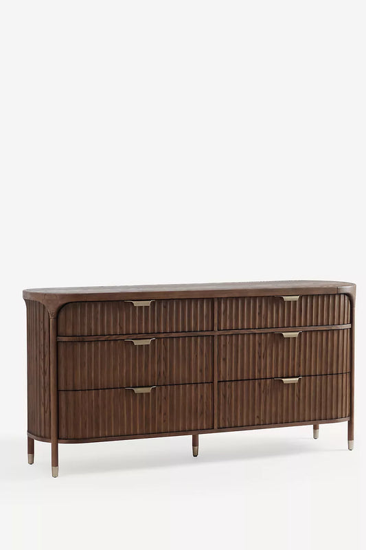 This appears to be a wooden six-drawer dresser, possibly from the brand Hansa Handicraft. It has a sleek, modern design with vertical grooves on the drawer fronts and elegant brass-finished handles. - Hansa Handicraft