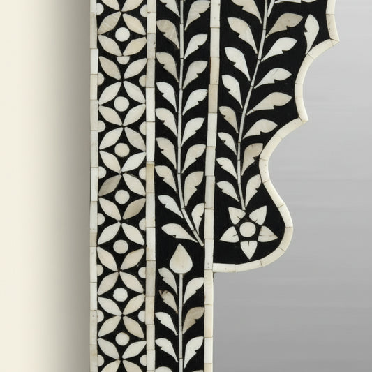 Decorative mirror with intricate black and white frame on a white background