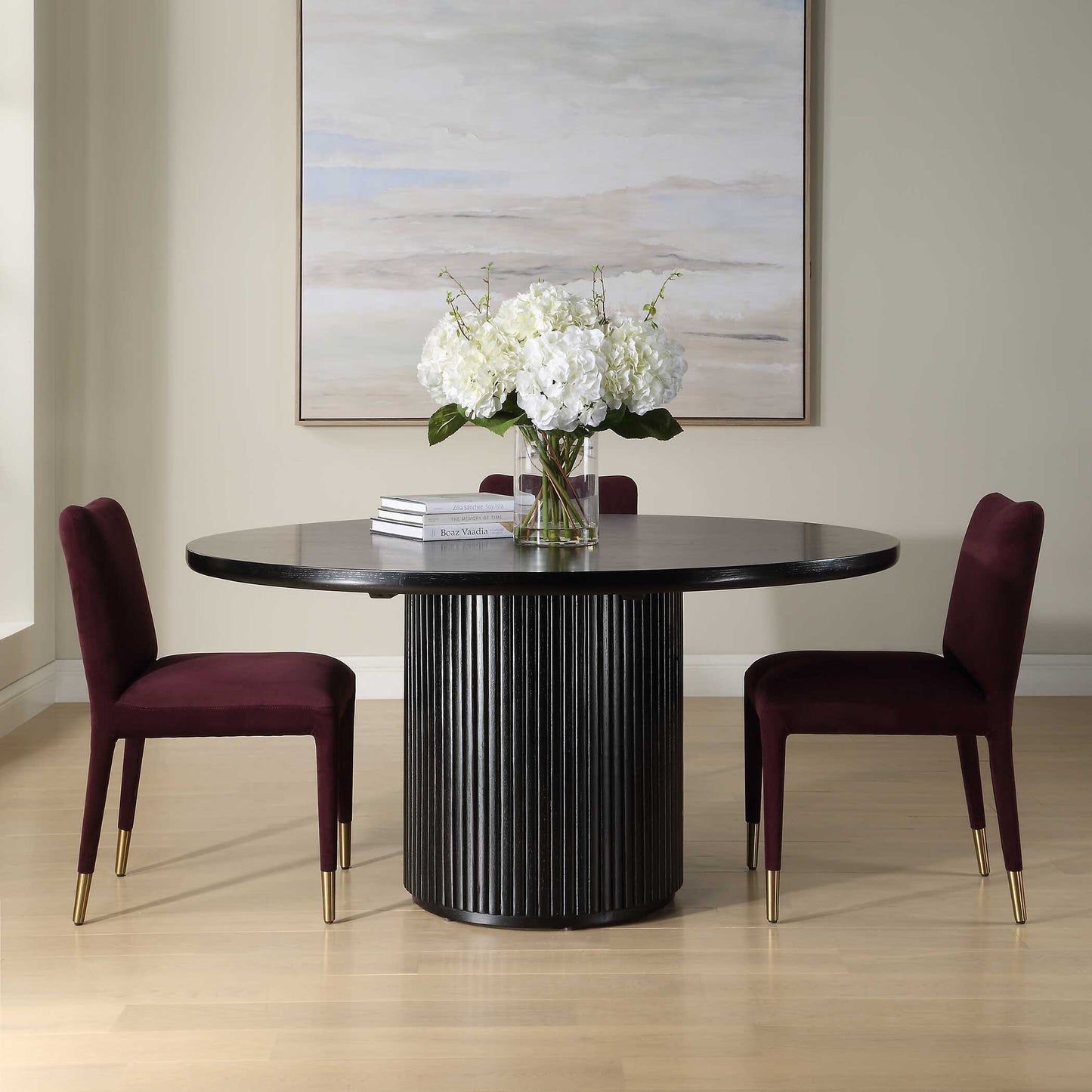 Dining room with a black round table and two purple chairs, featuring a vase of white flowers.