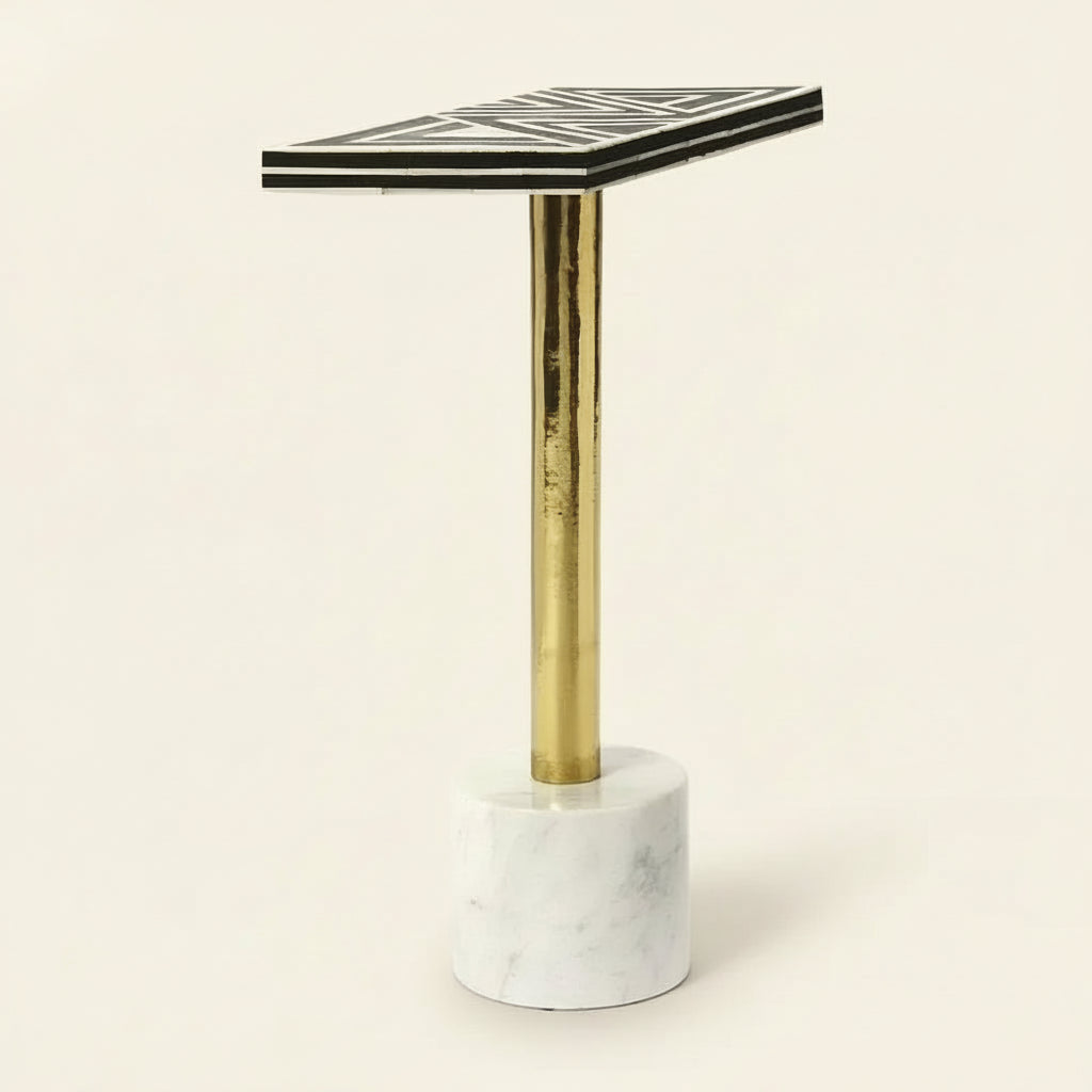 Small table with black and white geometric patterned top, gold leg, and marble base on a white background