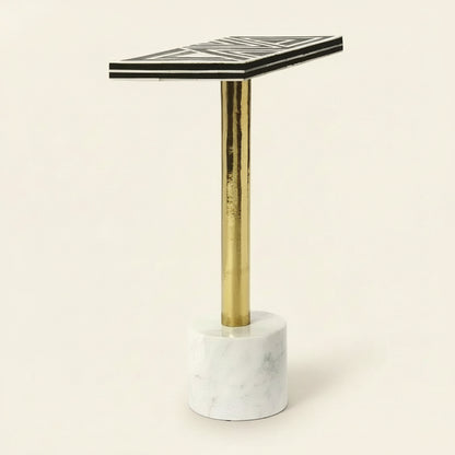 Small table with black and white geometric patterned top, gold leg, and marble base on a white background