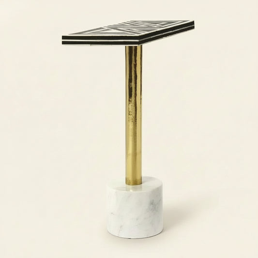 Small table with black and white geometric patterned top, gold leg, and marble base on a white background