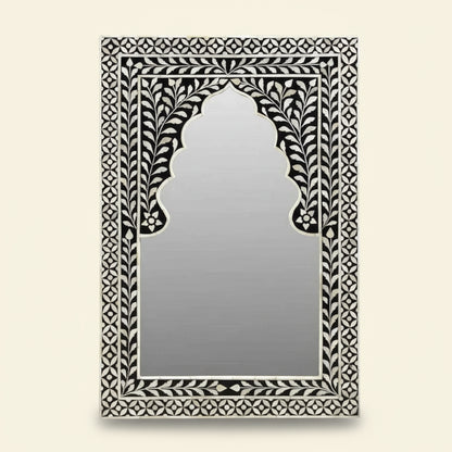 Decorative mirror with intricate black and white frame on a white background