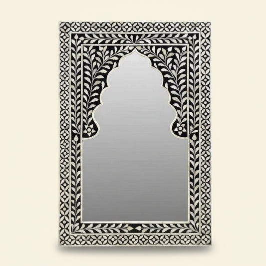 Decorative mirror with intricate black and white frame on a white background
