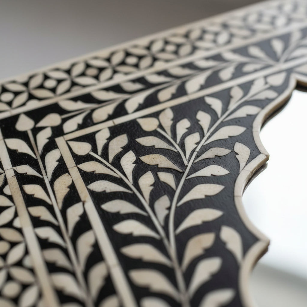 Decorative mirror with intricate black and white frame on a white background