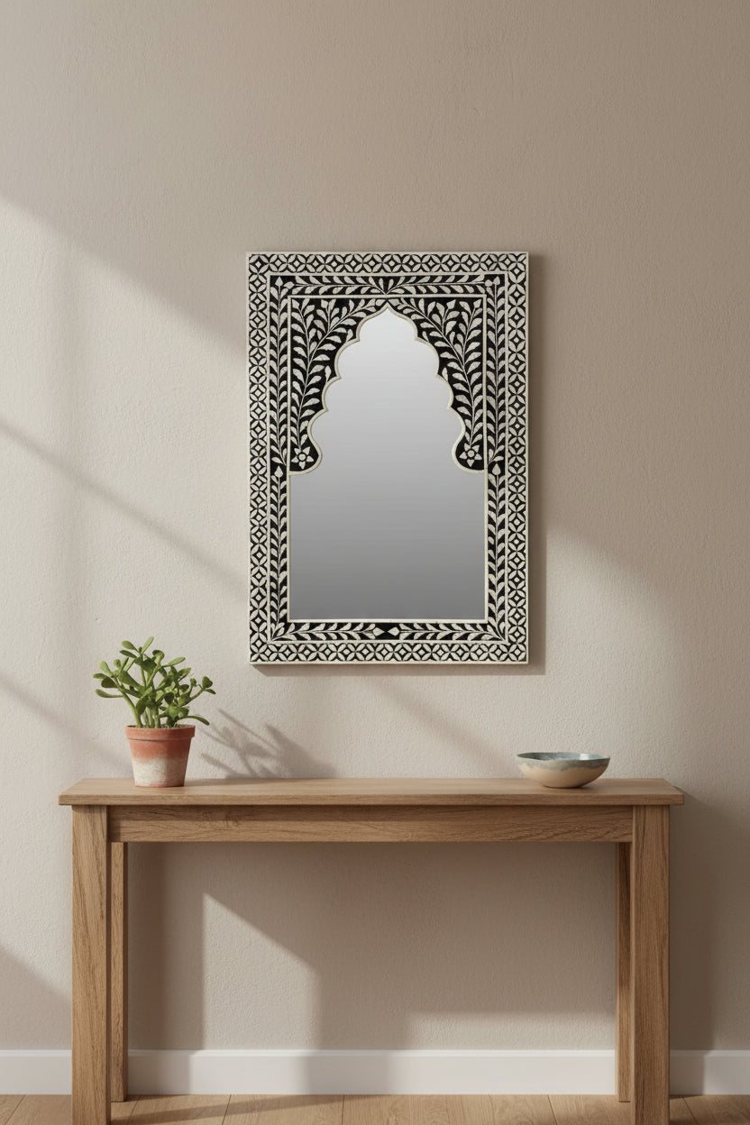 Decorative mirror with intricate black and white frame on a white background