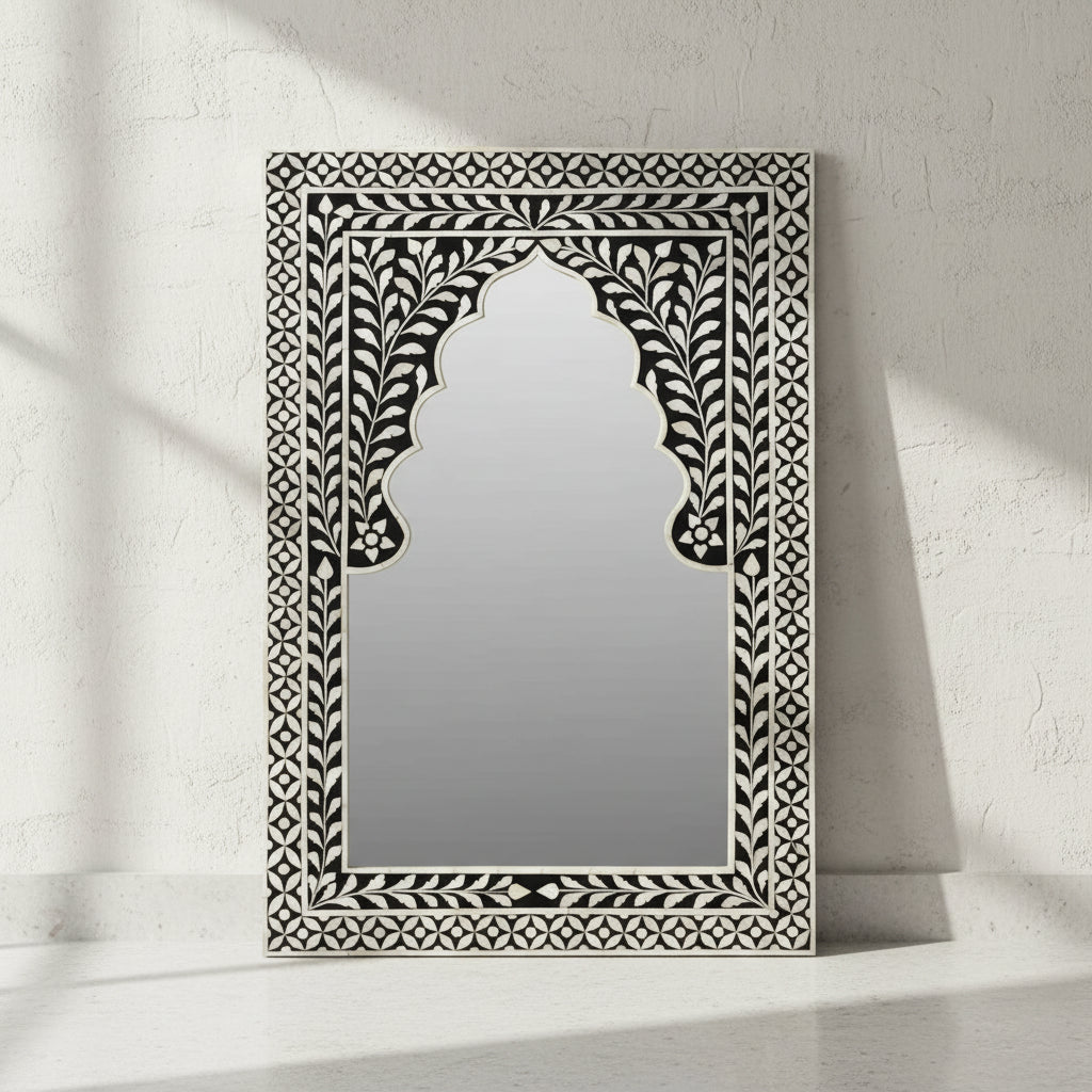 Decorative mirror with intricate black and white frame on a white background
