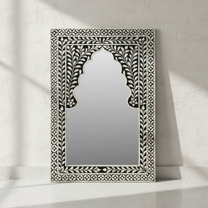 Decorative mirror with intricate black and white frame on a white background