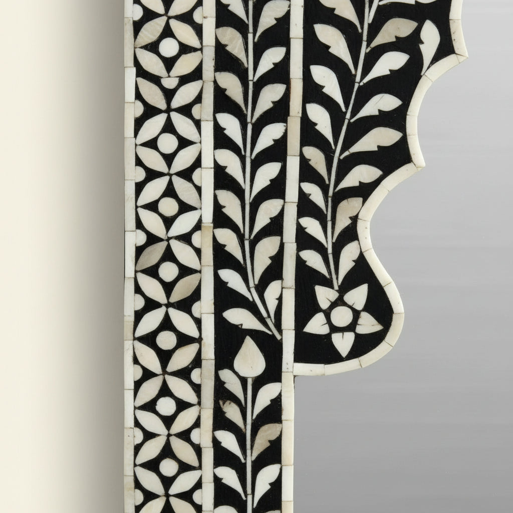 Decorative mirror with intricate black and white frame on a white background