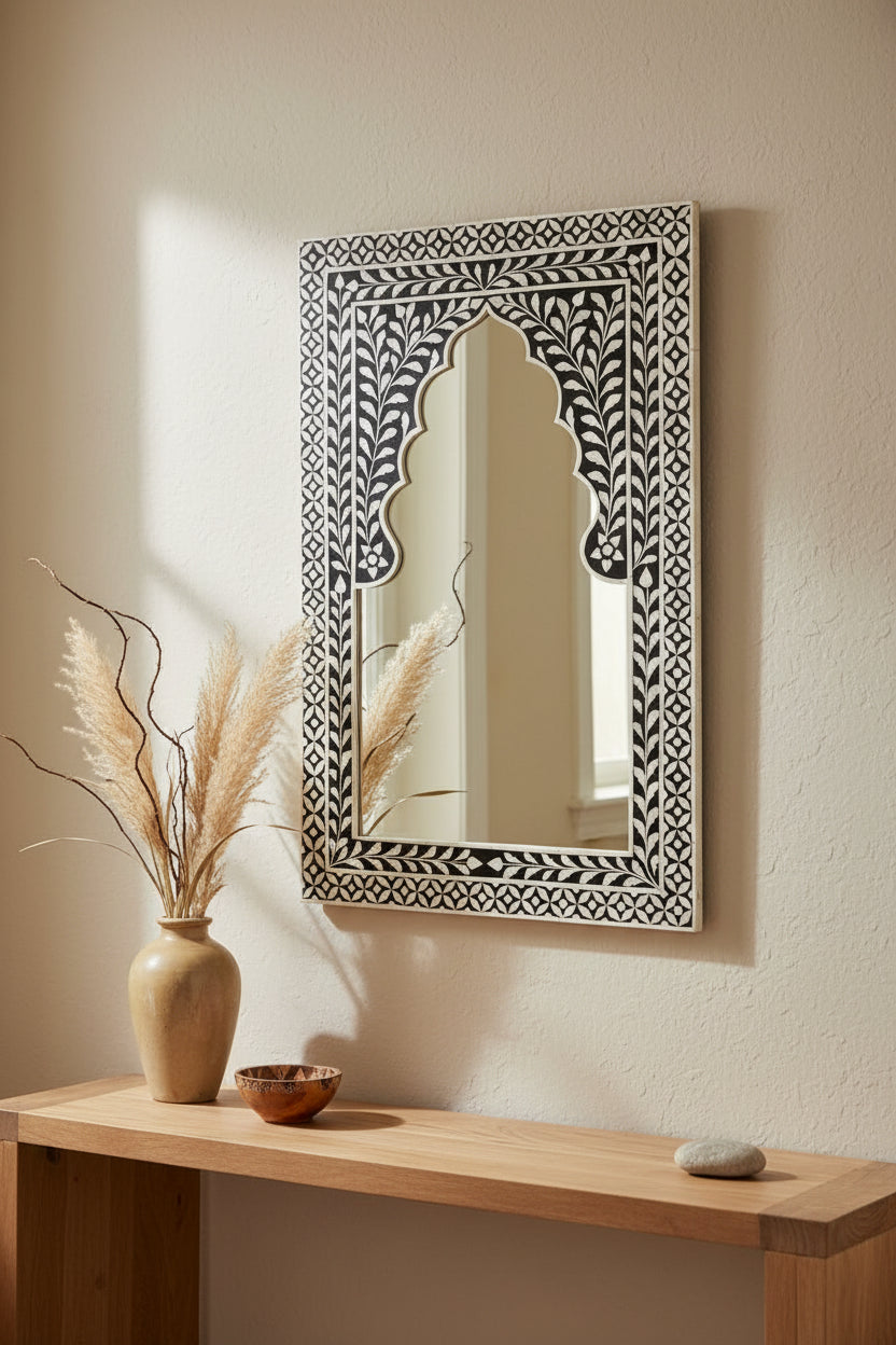 Decorative mirror with intricate black and white frame on a white background